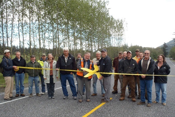 Bob Jarman cuts a ceremonial ribbon to mark the completion of the Mount Baker Road road improvement project.