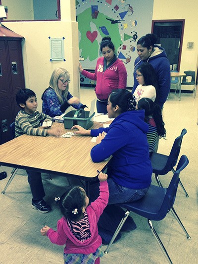 ELL teacher Robin Freeman helps Isaac Figueroa teach families an addition practice game.