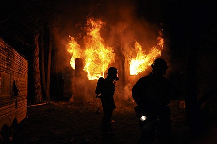 Fire officers watch crews carefully as fire blows out back windows of the structure.