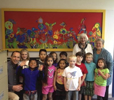 Michelle DeLong (far right) helped Mathew Chasanoff’s kindergarten class make “Party Birds” (shown behind students) for the OIEF “Food for Thought” event. Donor Millie Vaccarella (right) bought the piece during the live auction.  She then donated it back to the school so the class could see it every day as they came into school.