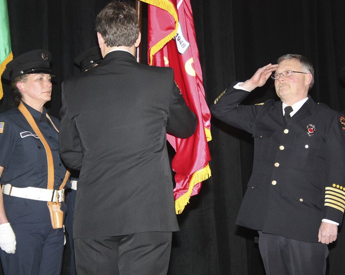 Orcas Fire Chief Mike Harris passes the OIFR flag to Kevin O’Brien as a symbol of the change in command.