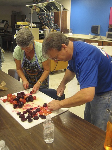 Farm to Cafeteria volunteer Geri Turnoy and Jim Wilde of Lowe’s cutting up plums.