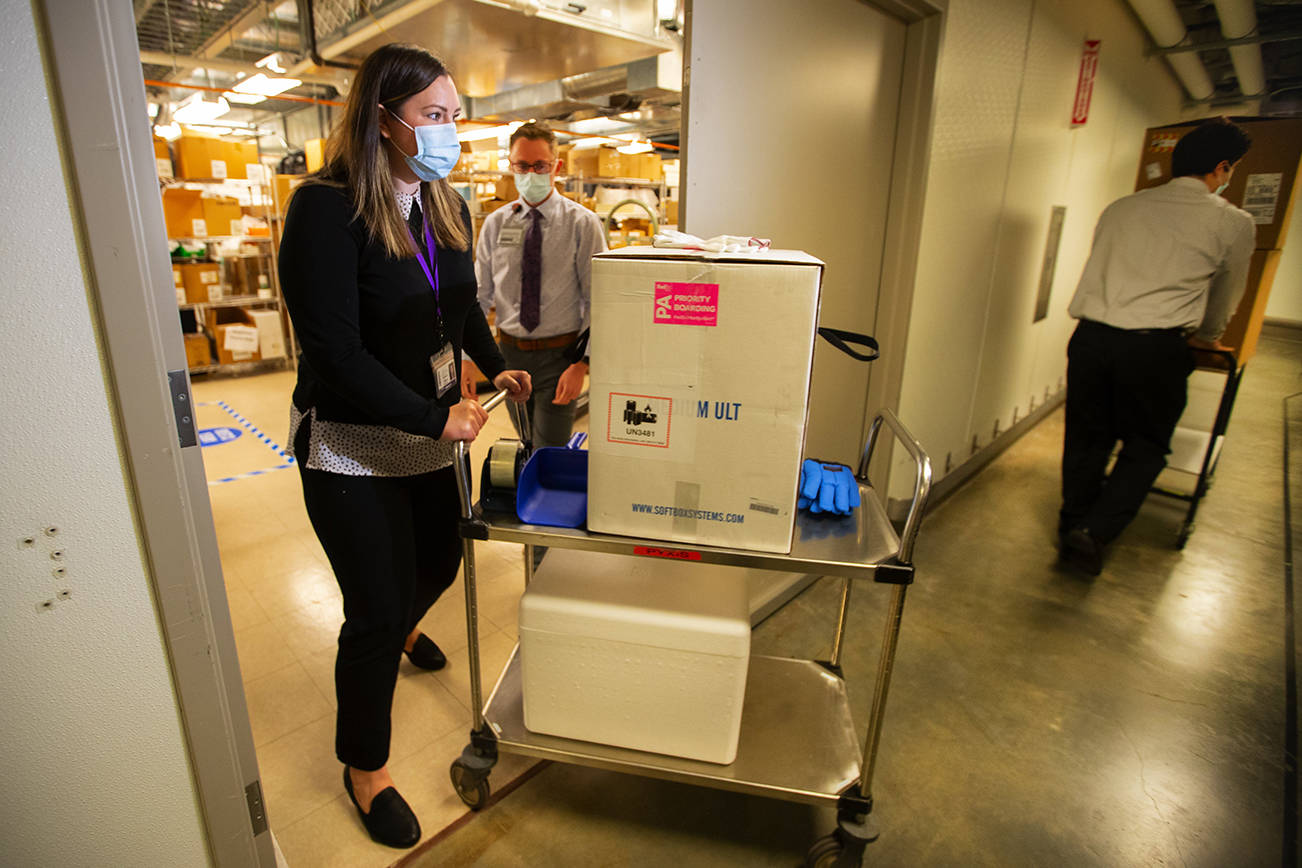 UWMC Pharmacy Manager Christine Meyer puts a tray of 975 doses of Pfizer’s coronavirus vaccine into the deep freeze after the vaccine arrived at UW Medicine’s Montlake campus Monday morning, Dec. 14, 2020. These are among the first to be distributed in Washington state. A total of 3,900 doses arrived at the UW on on Dec. 14 that will be distributed among UW Medicine’s four hospital campuses. (WA DOH POOL/contributed photo)