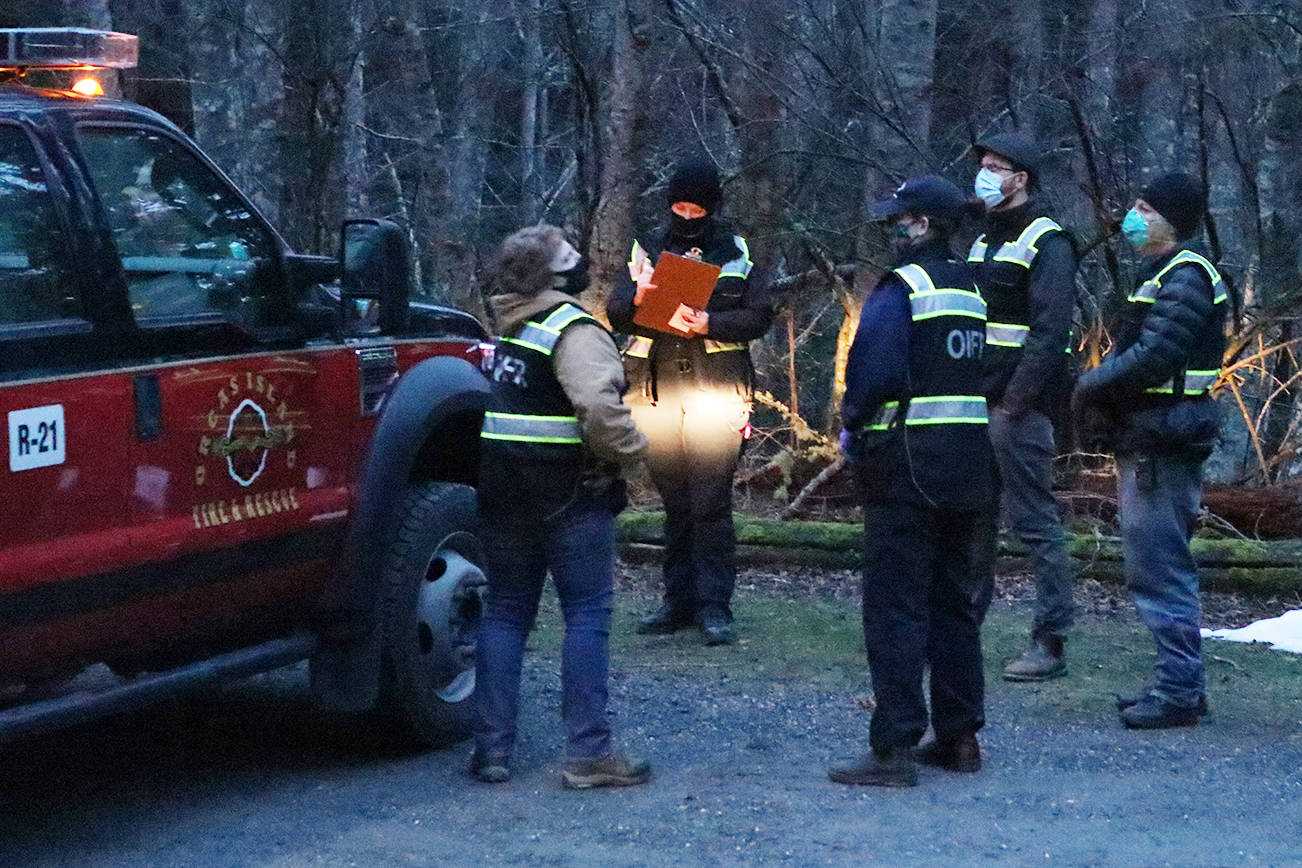 A search team discusses the game plan to find a missing person at the parking area near the lagoon in Moran State Park after sunset on Feb. 19, 2021. (Mandi Johnson/Staff photo)