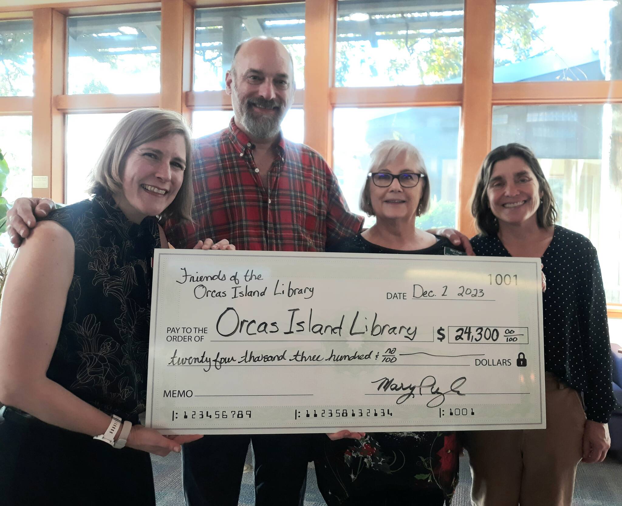 FOIL Board Members Michael Armenia, Mary Pugh, and Kathy Morris present the library director Ingrid Mattson (far left) with a check for books and programs for 2024.